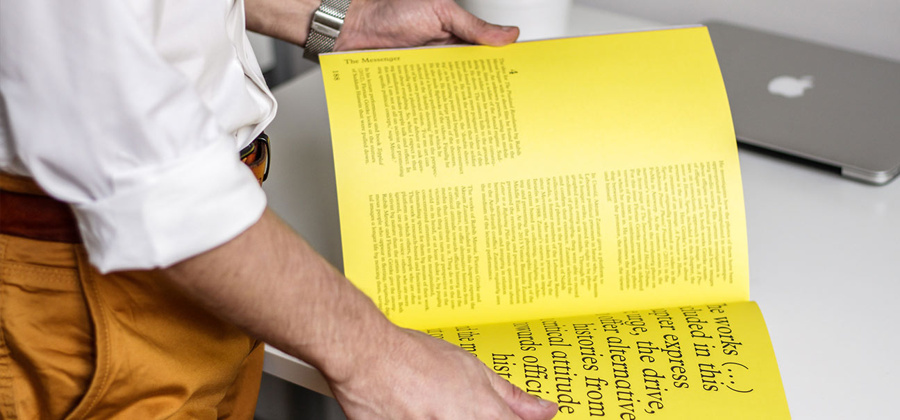 Ein Mann, hemdsämlig, schägt die Doppelseite eines Magazins auf